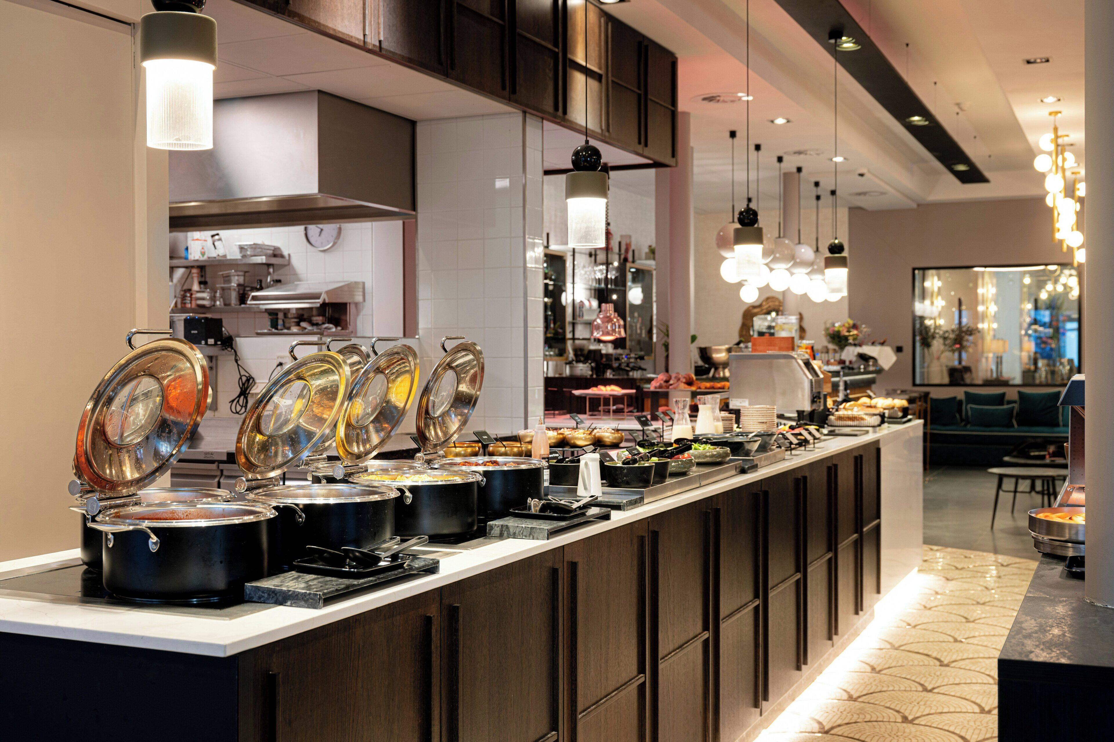 A buffet setup with multiple food stations, a kitchen area, and a seating area with a view.