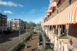A street view with a row of buildings, some with orange-striped awnings, and a clear blue sky. - The Manor Amsterdam (Amsterdam)
