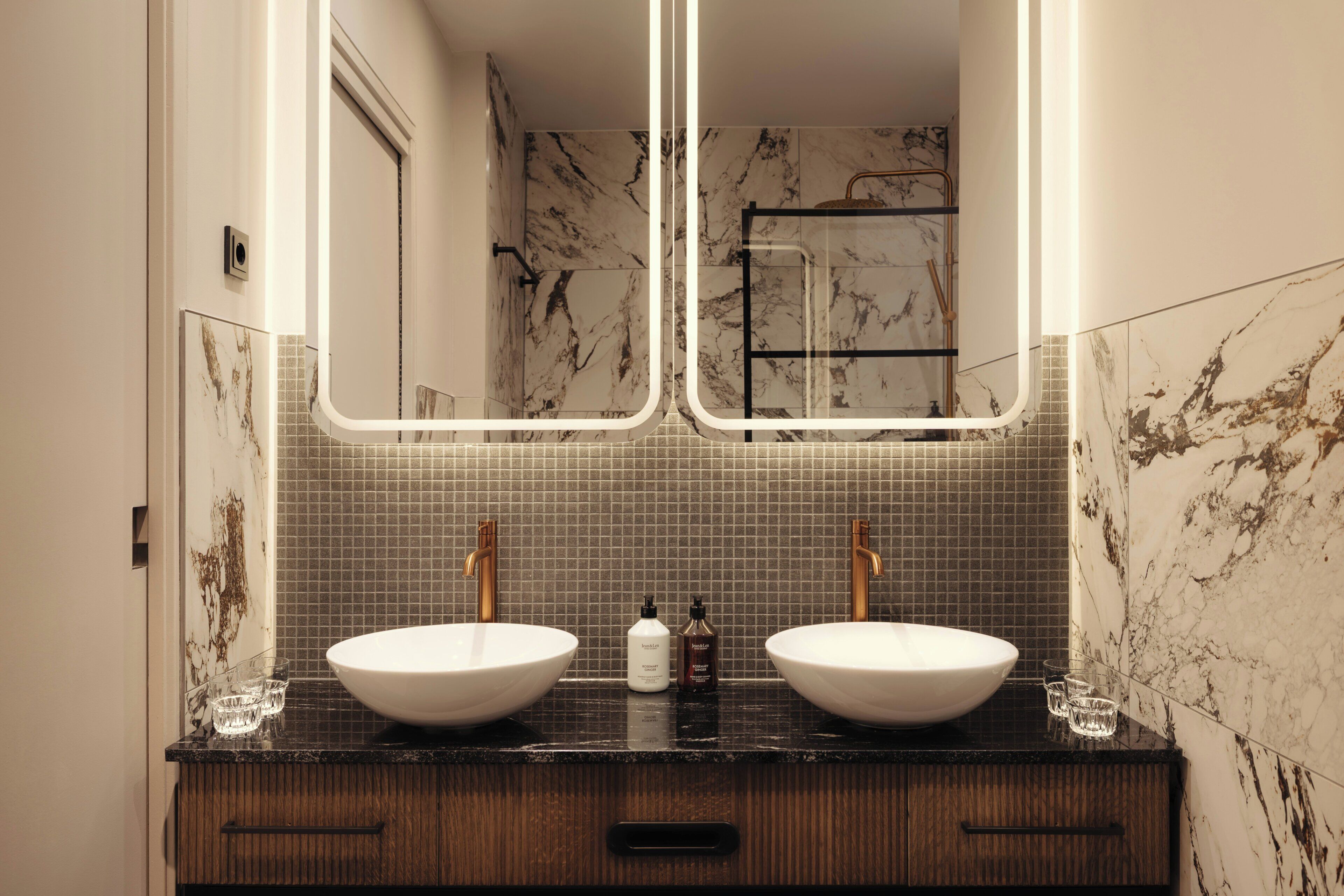 Een badkamer met twee wastafels, een spiegel en een douche.