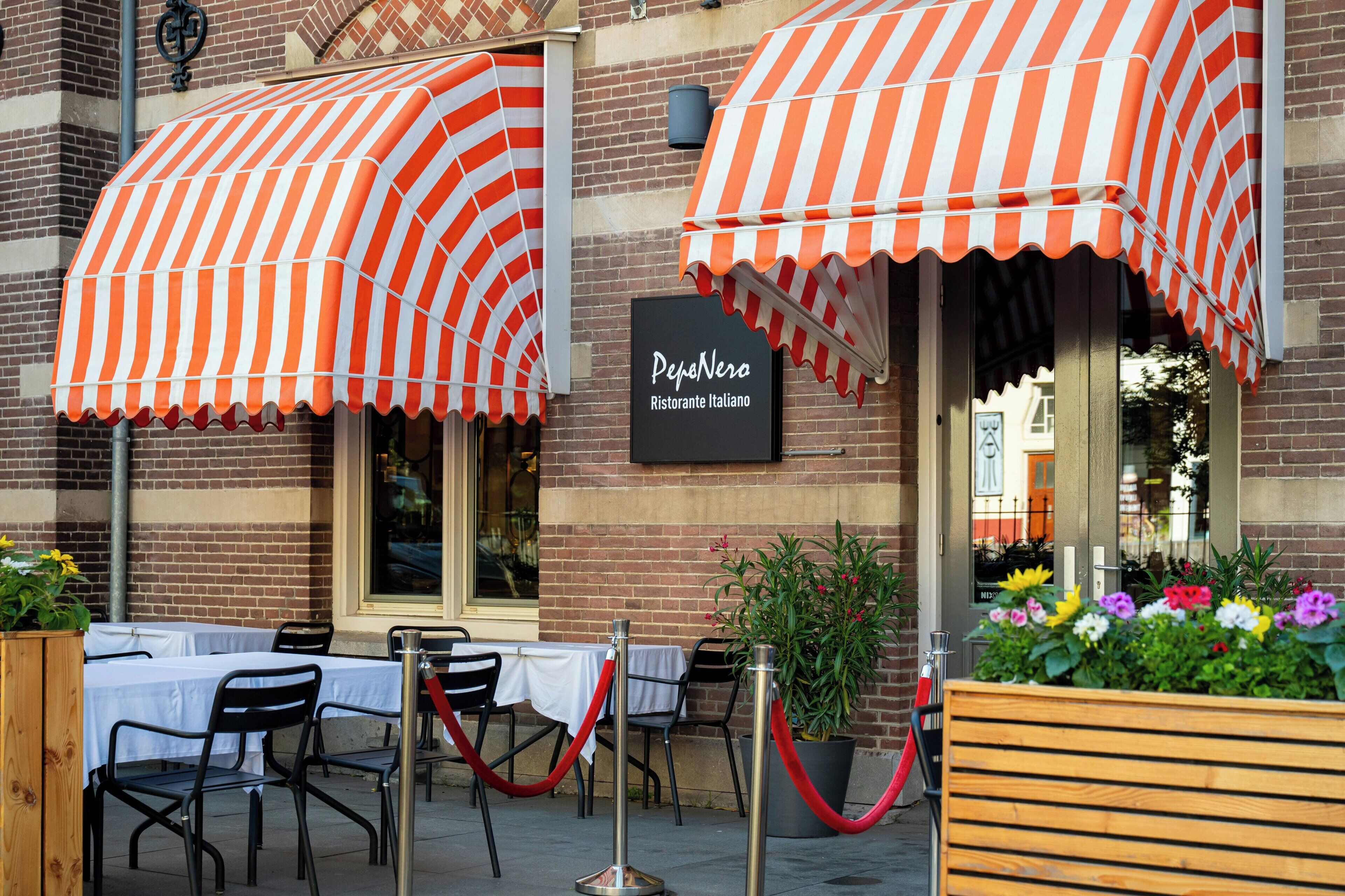 Restaurante com área externa, toldos listrados e uma placa que diz 'PepaNero Ristorante Italiano'.