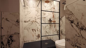 Une salle de bain avec des murs en marbre, un sol noir et des toilettes blanches.
