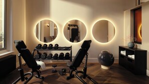 Un gimnasio con equipo de ejercicio, un estante de mancuernas y un jarrón grande.