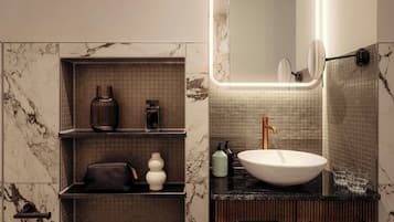 Un baño con pared de mármol, encimera negra, lavabo blanco y un espejo.