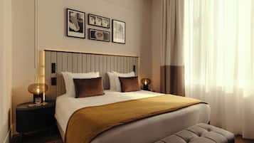 A hotel room with a large bed, bedside tables with lamps, a headboard, and framed pictures on the wall.