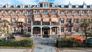 Un edificio histórico con una entrada central, múltiples ventanas y una bandera.