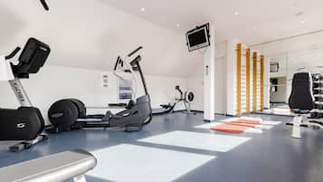 Une salle de sport moderne équipée d’appareils de cardio, de machines de musculation et d’un écran de télévision.