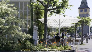 An outdoor cafe with tables and chairs, surrounded by greenery and flowers. - Hotel Reutemann - Seegarten (Lindau)