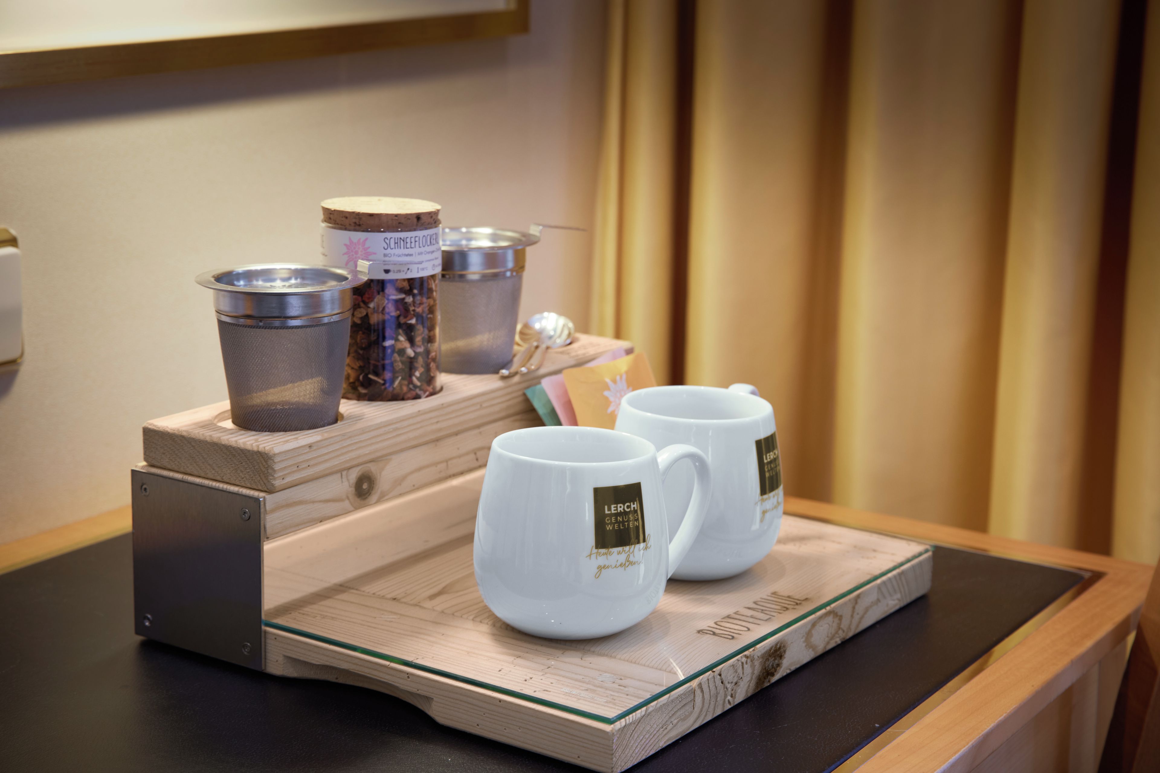 A tray with two white mugs and two containers on a wooden table.