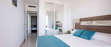 A hotel room with a large bed, a wooden headboard, and a view of the hallway.