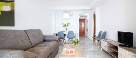 A modern living room with a grey sofa, a wooden coffee table, and a TV on a wooden stand.
