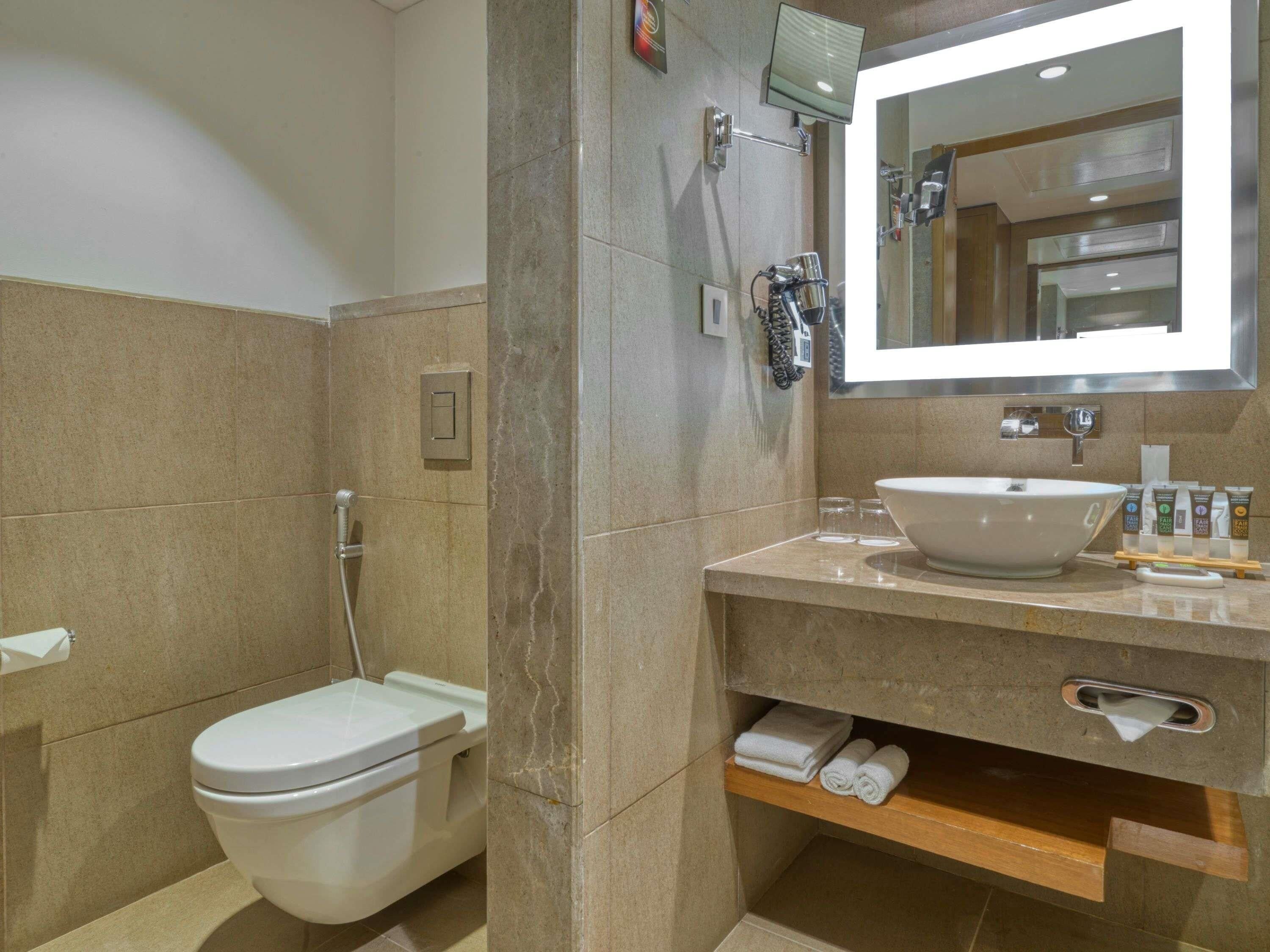 Ein Badezimmer mit Toilette, Waschbecken, Spiegel und Dusche.
