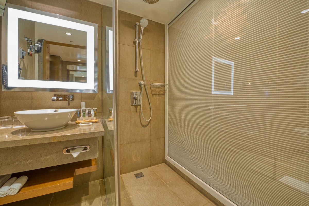 A modern bathroom with a large mirror, a sink, and a shower enclosure.