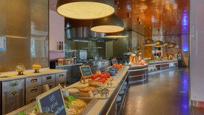 Zona de buffet con diferentes estaciones de comida, incluyendo un letrero que dice 'Pasta Fresca en Vivo'.