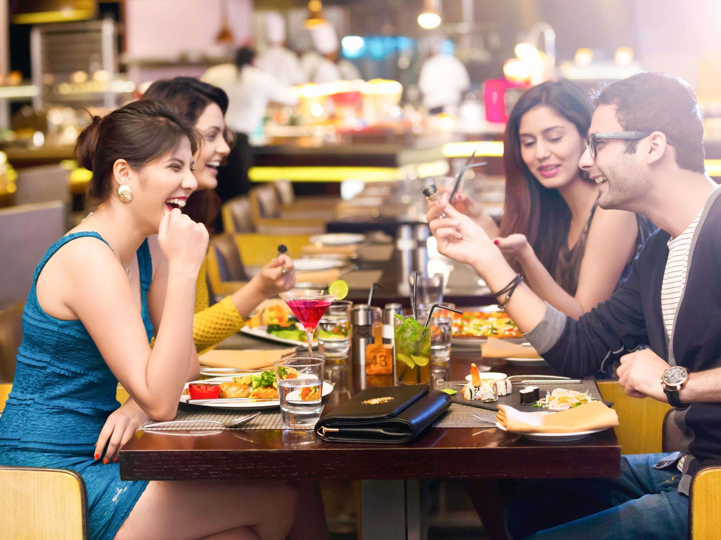 Un groupe de personnes est réuni dans un restaurant, et une variété de plats et de boissons sont disposés sur la table.