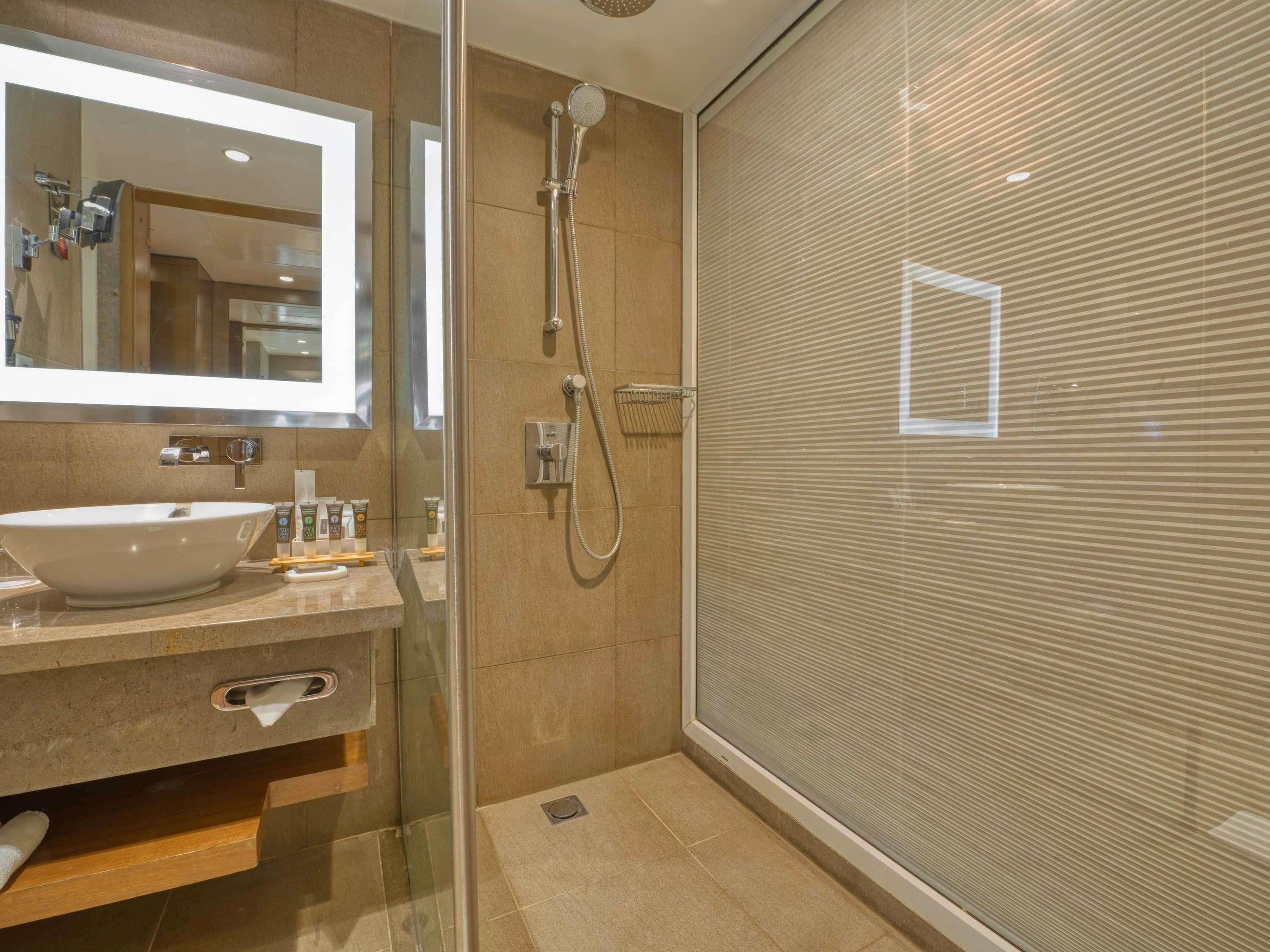Een moderne badkamer met een groot wastafel, spiegel en douche.