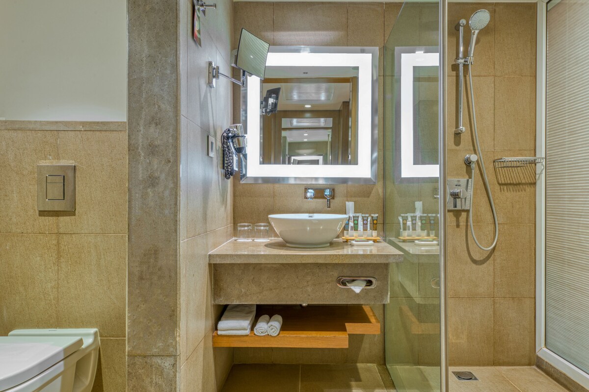 A modern bathroom with a large mirror, a sink, and a shower.