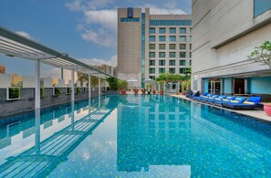 A swimming pool with lounge chairs and a building in the background.