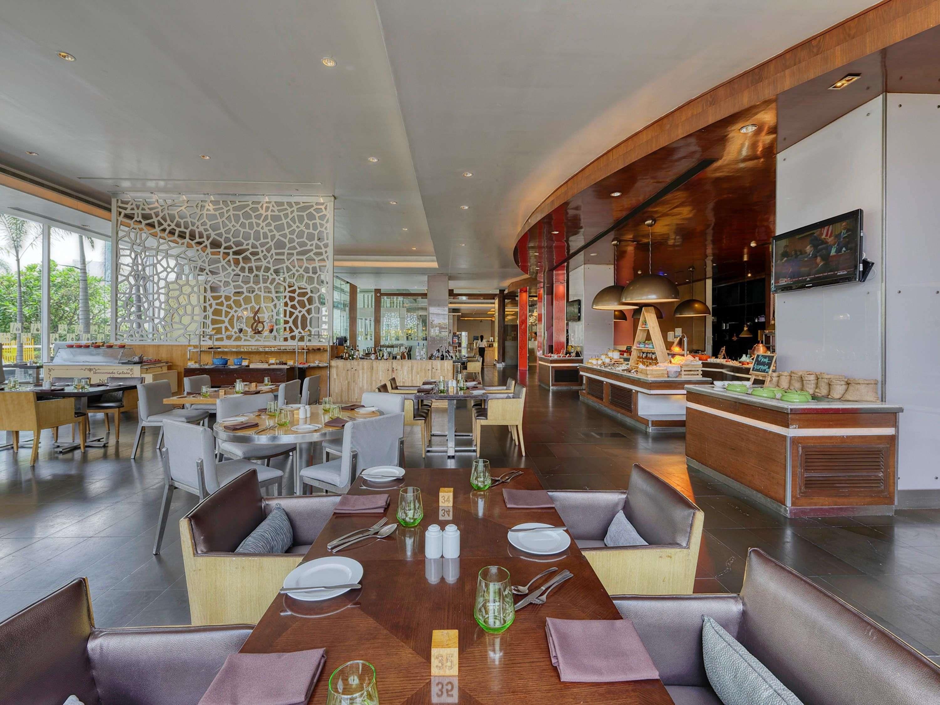Un restaurante espacioso con techos altos, mobiliario moderno y una zona de bar central.