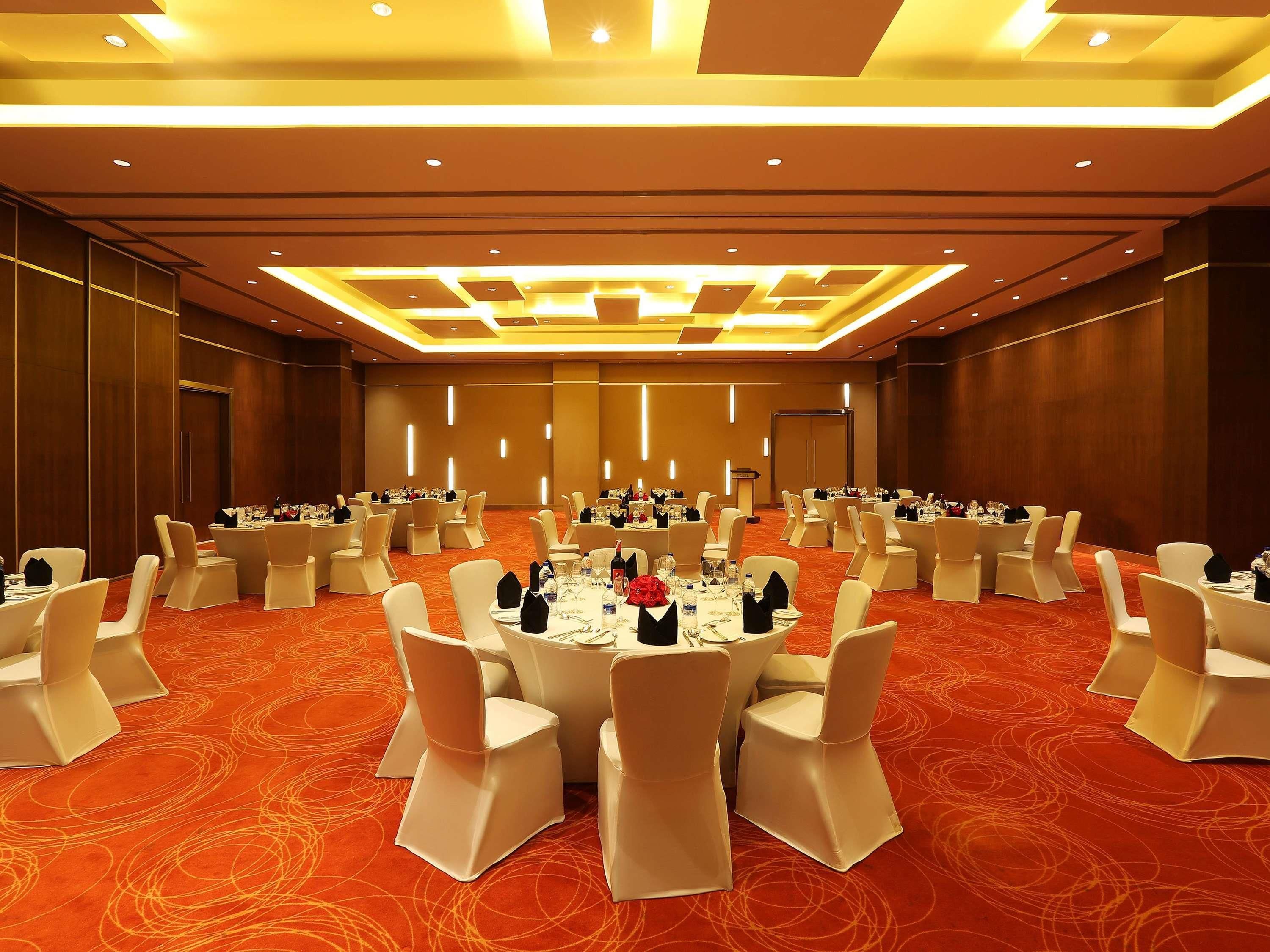A conference room with round tables, white chairs, and a red carpet.