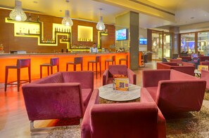 A bar area with a bartender, red velvet chairs, and a round table with a decorative item.
