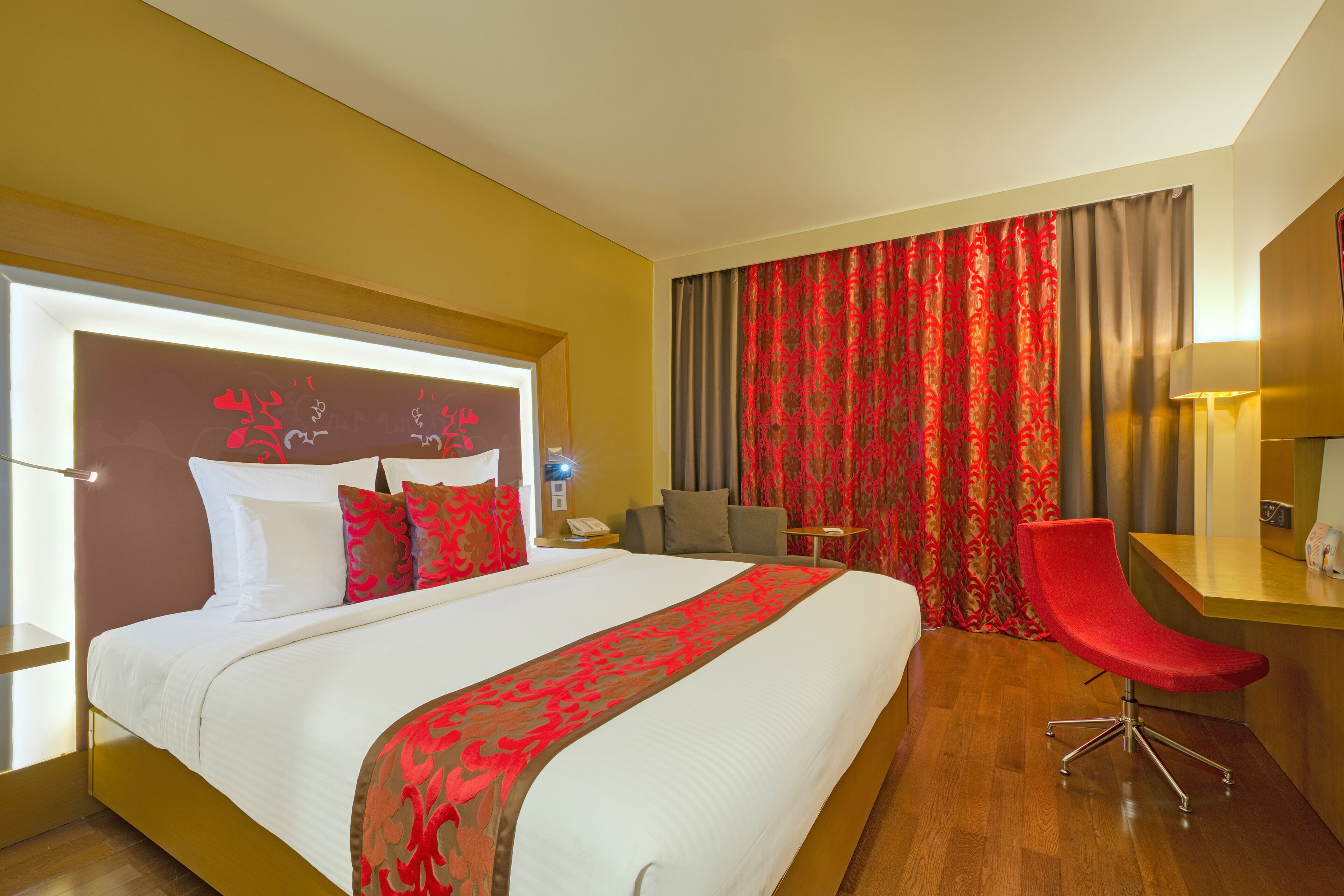 Una habitación de hotel con una cama grande, un escritorio con silla y una lámpara de escritorio.