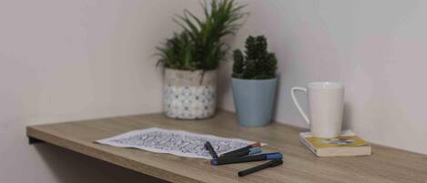 A wooden desk with a white mug, a blue potted plant, and a small white pot with another plant.