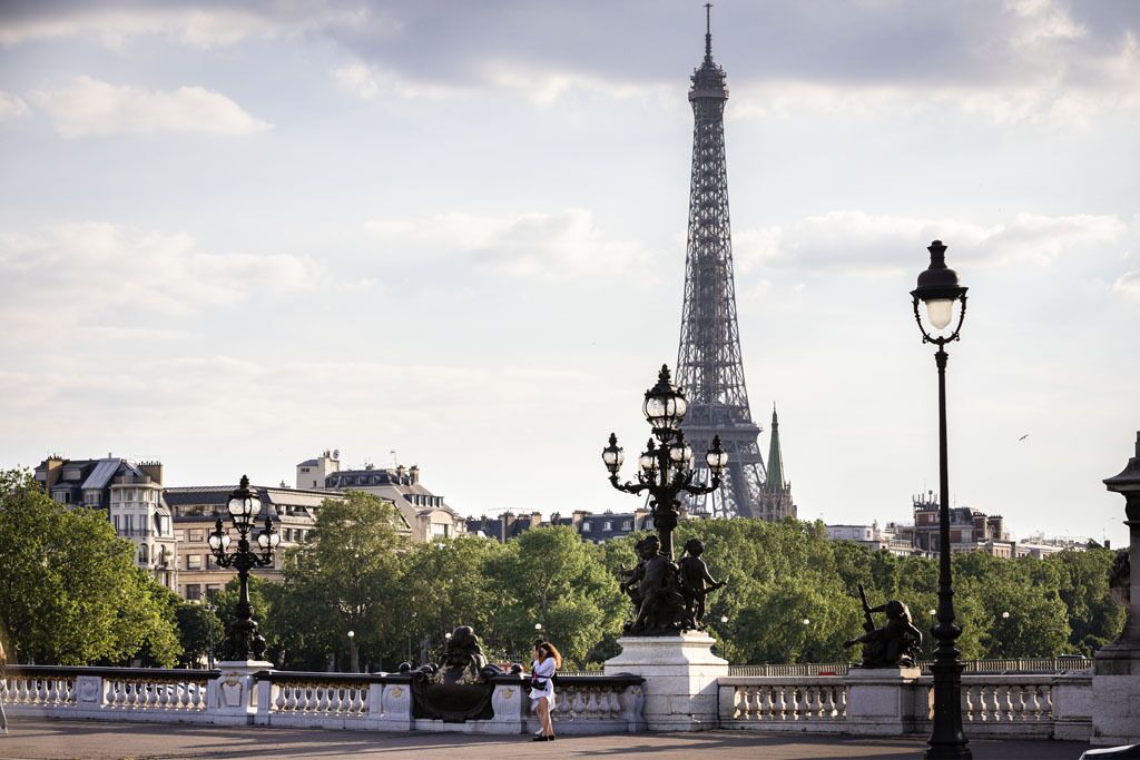A view of the Eiffel Tower with a statue and lamp post in the foreground.
