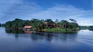A calm lake with a small dock and a house surrounded by lush greenery.