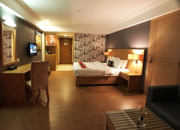 A hotel room with a bed, bedside tables, a desk, a chair, and a TV. - Discovery Hotel (Phnom Penh)