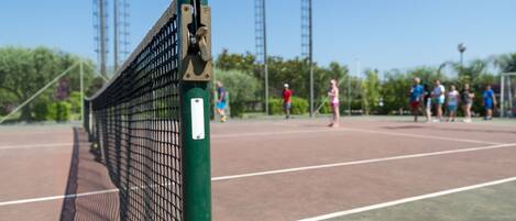 A tennis court with a net in the foreground and people playing in the background.
