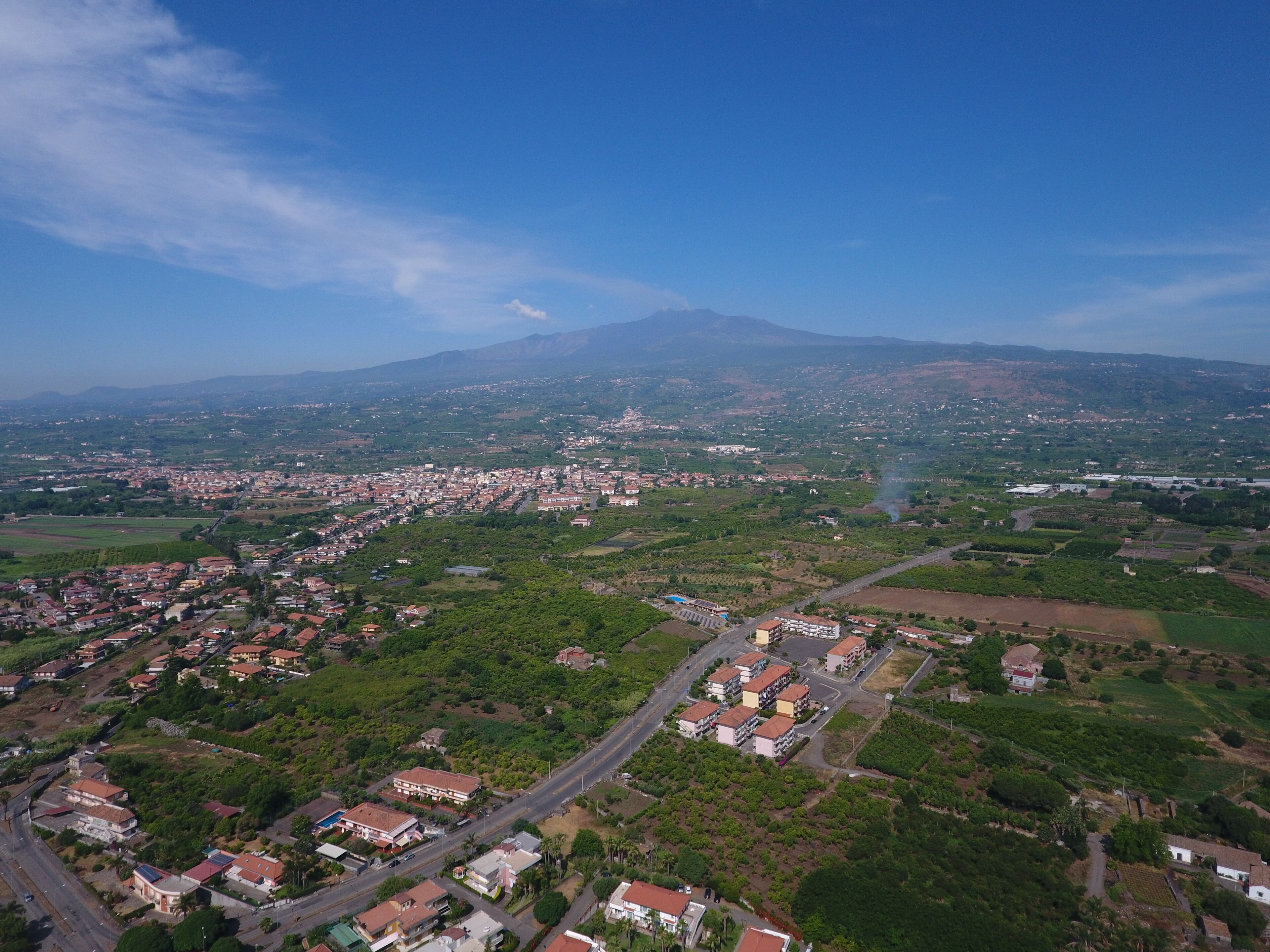 An aerial view of a town with residential buildings, roads, and green areas.