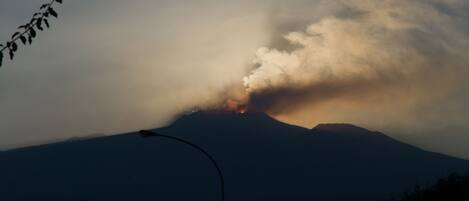 A mountain with a visible smoke plume, suggesting volcanic activity.