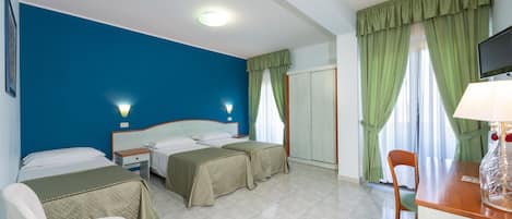 A hotel room with two beds, a desk, a chair, and a TV.