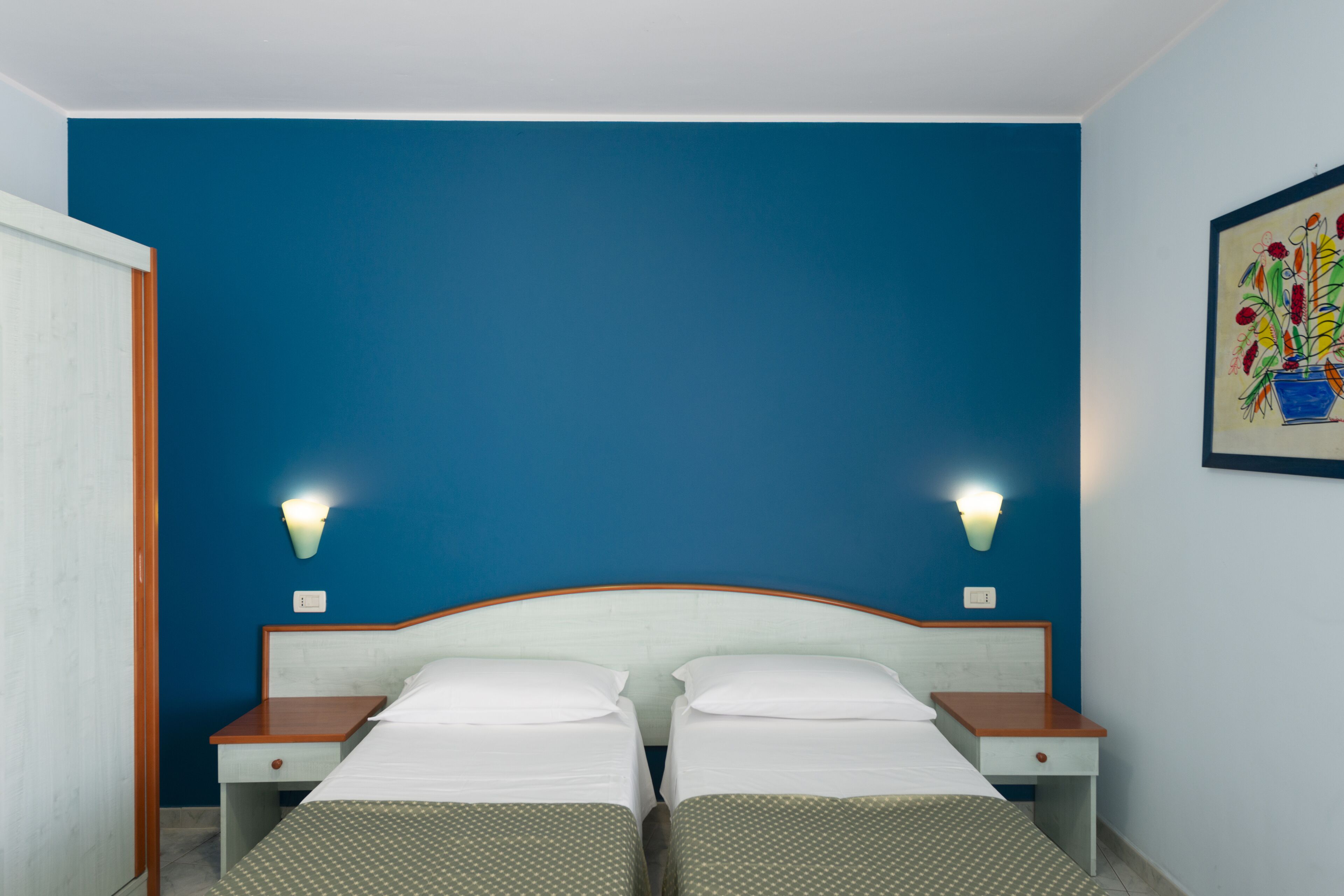 A double room with two beds, a wooden headboard, bedside tables, and wall-mounted lights.