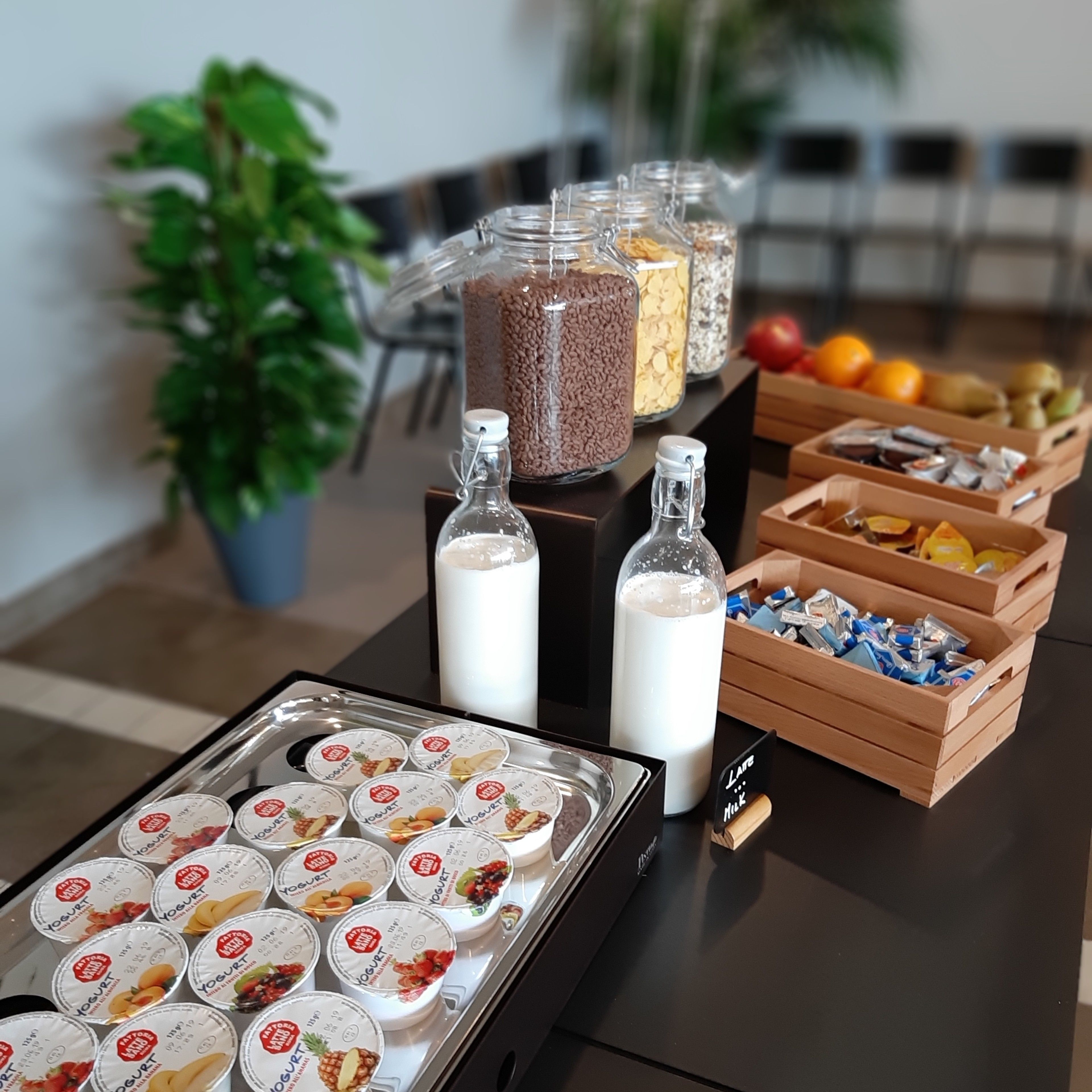 A buffet table with various food items including yogurt, milk, and snacks.