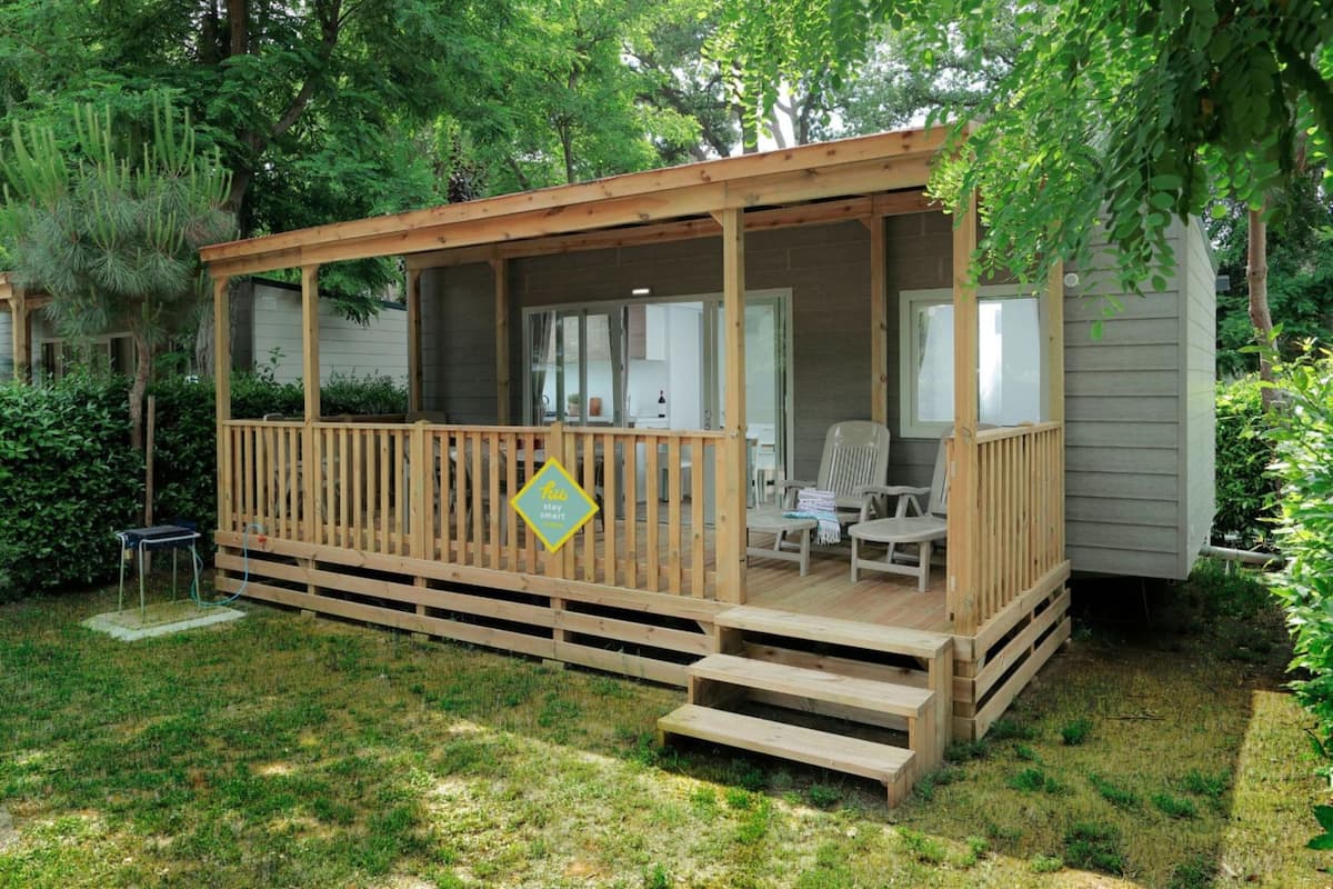 A wooden decked cabin with a covered porch, a small table, and a chair.
