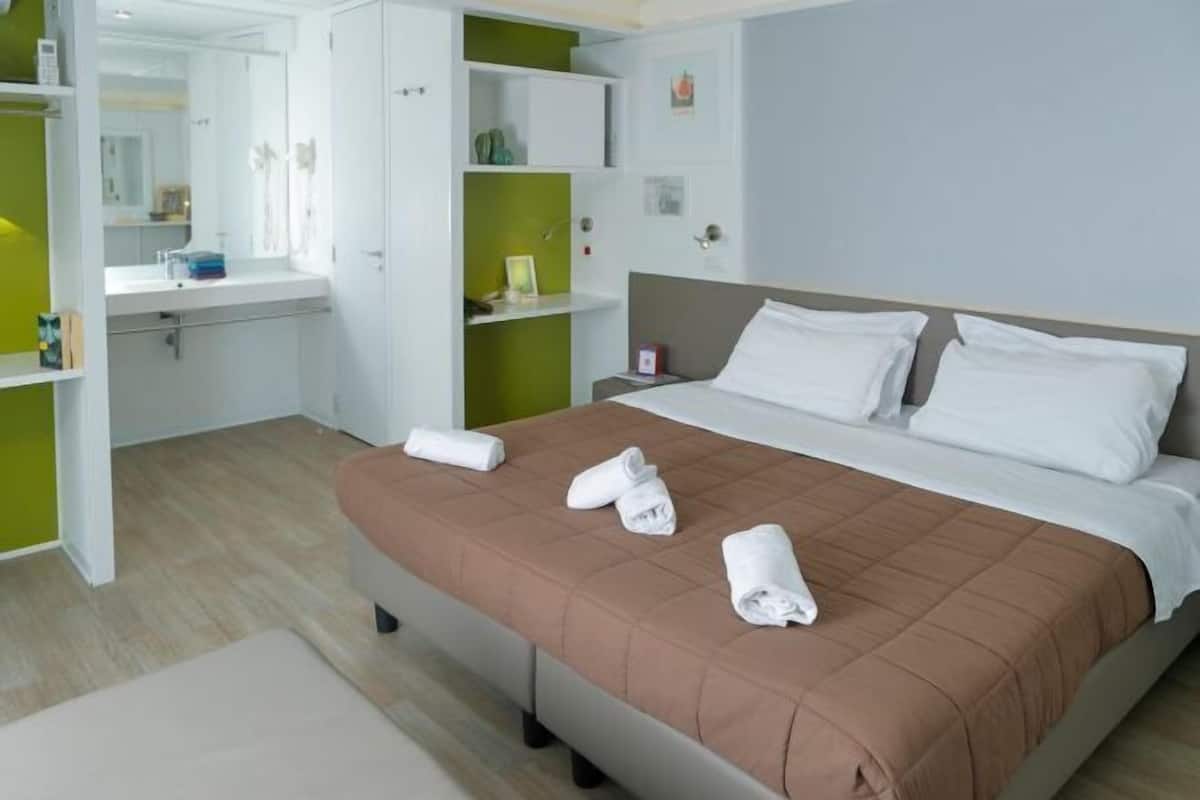 A hotel room with a bed, a bathroom, and a small seating area.