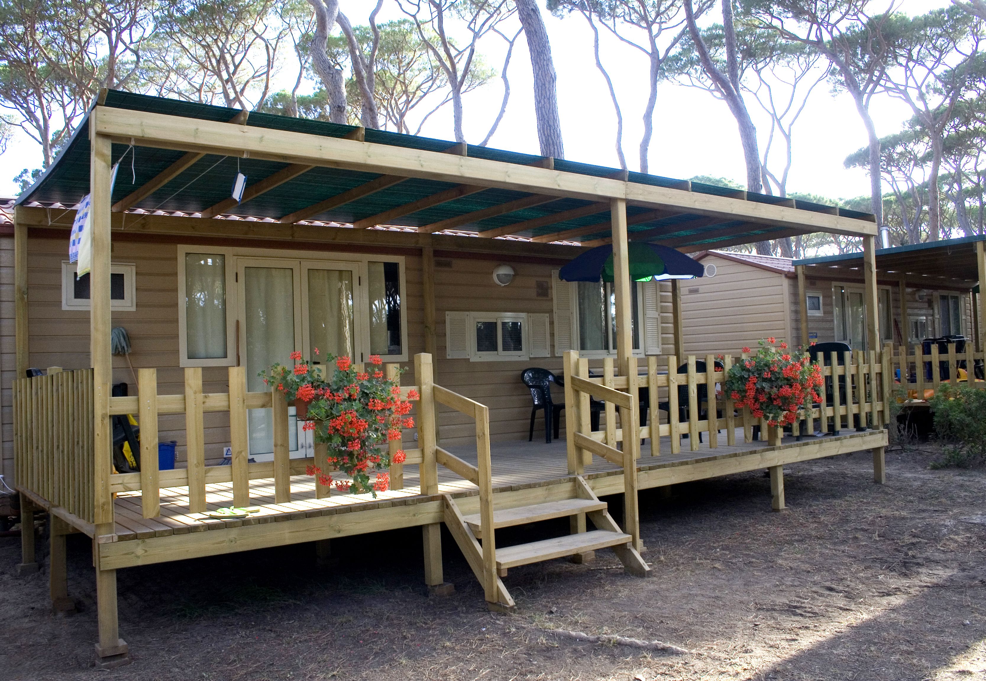 A wooden cabin with a porch, steps, and a covered area.