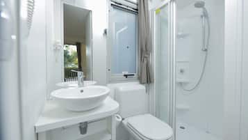 Een moderne badkamer met een wit wastafelmeubel, toilet en een douchecabine met glazen wanden.