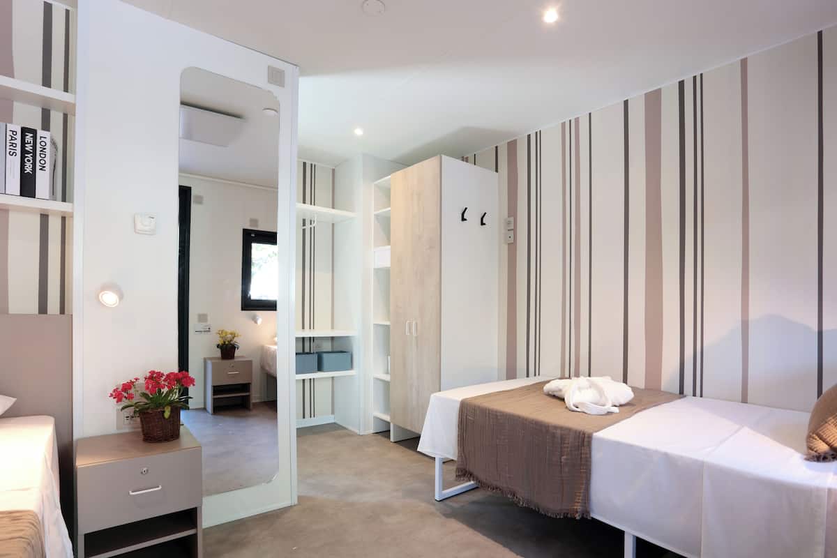 A bedroom with a bed, bedside table, wardrobe, and a mirror.