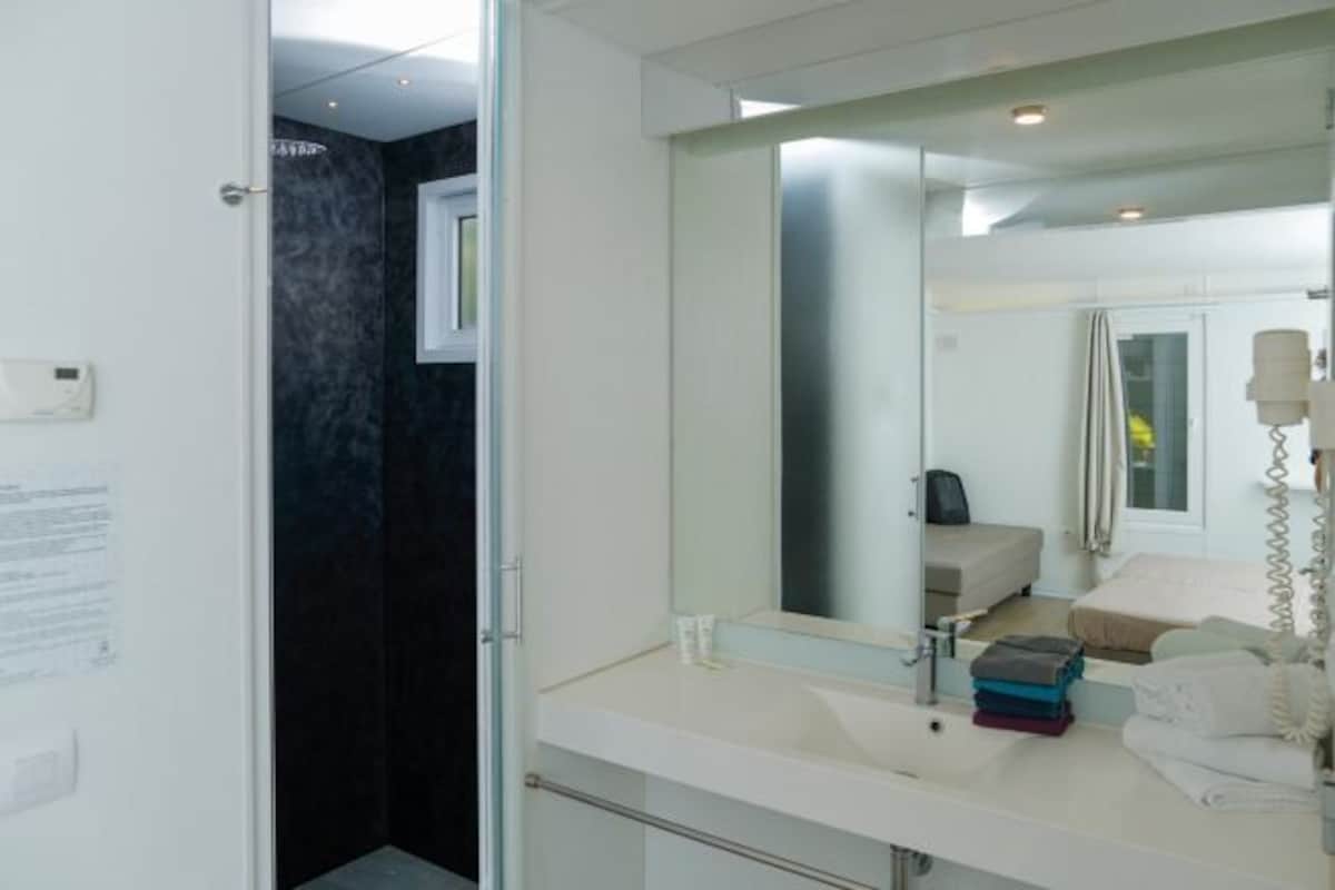 Un baño moderno con un espejo grande, un lavamanos y un perchero para toallas.