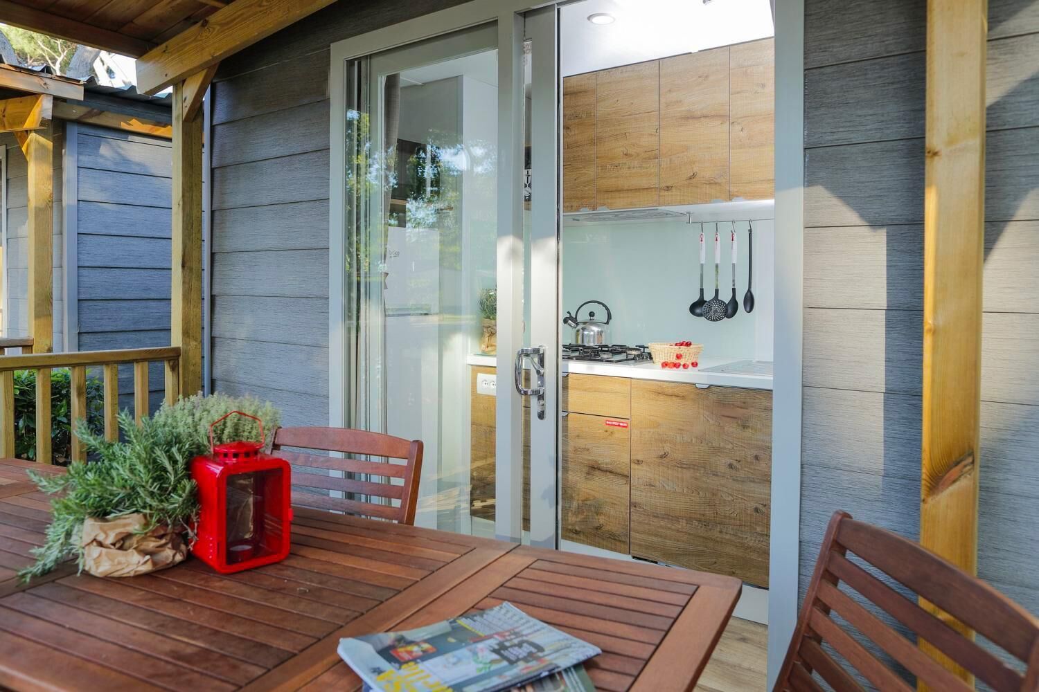 A wooden deck with a table and chairs, a red lantern, and a potted plant.