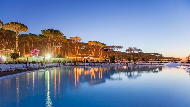 A serene pool area with lounge chairs and trees in the background. - Fabulous Village (Rome)