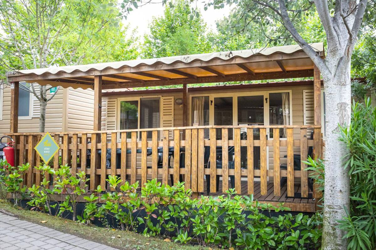 A wooden cabin with a covered porch, a fire hydrant, and a 'Stay Easy' sign.
