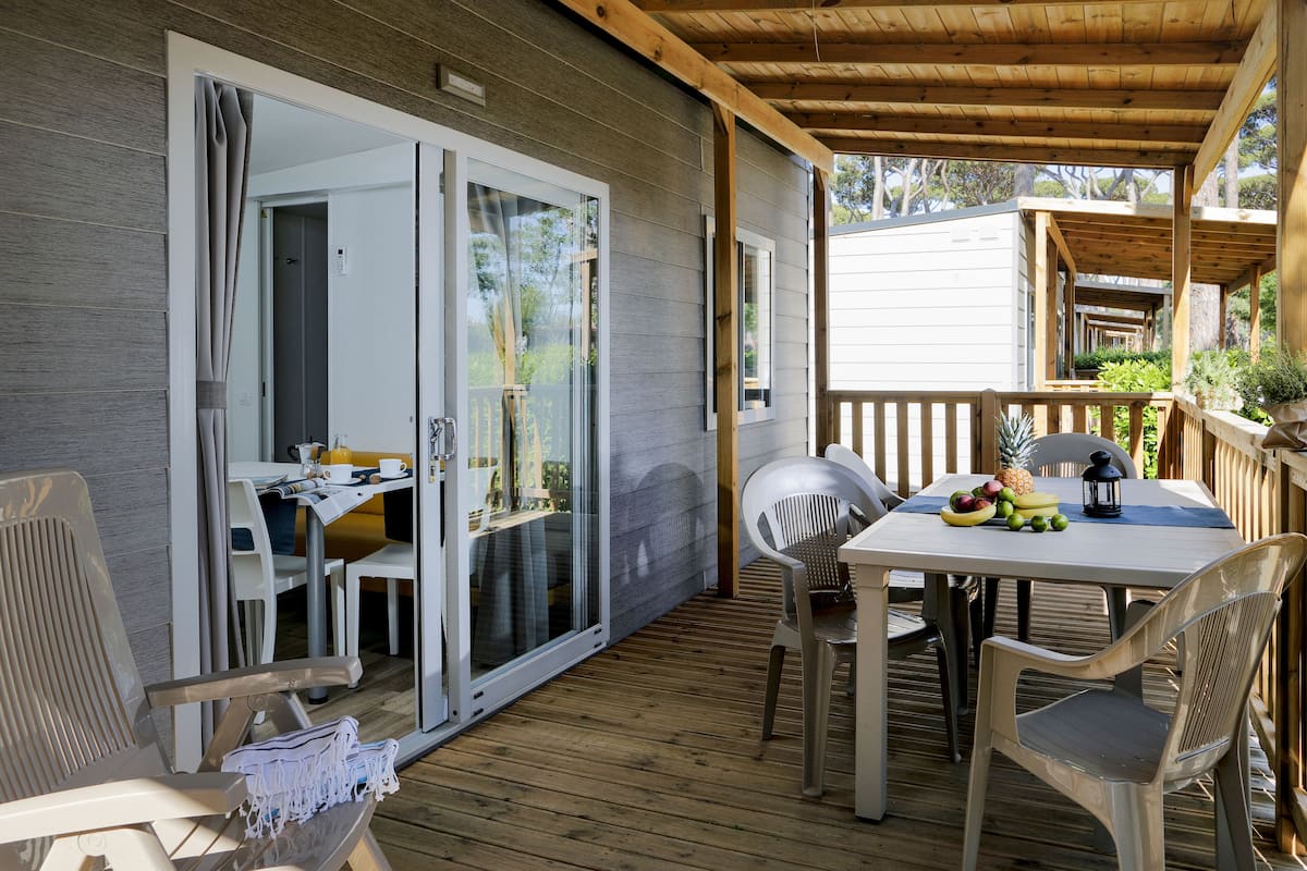 A covered outdoor area with a table, chairs, and a sliding glass door leading to an interior space.