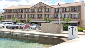 A hotel named MIRAMARE with multiple balconies, a swimming pool, and a parking area.