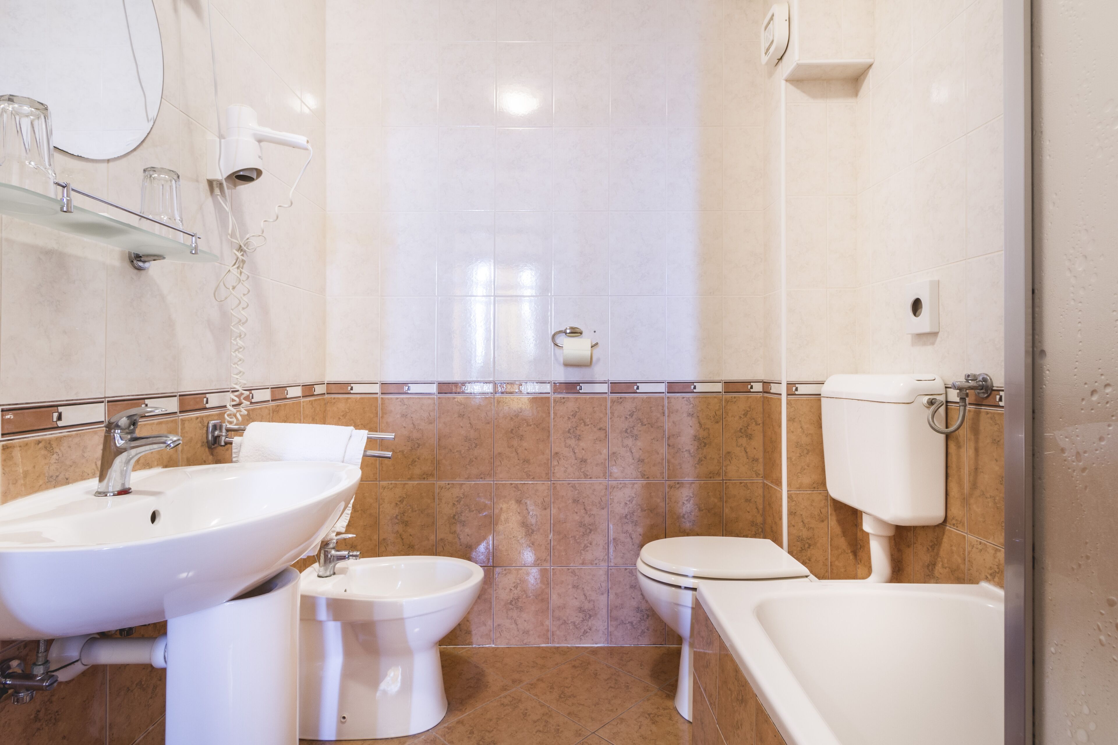 A bathroom with a sink, bidet, toilet, and bathtub.