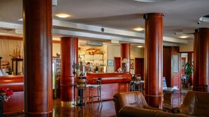 A spacious lobby with high ceilings, large wooden columns, leather seating, a bar area, and a reception desk.