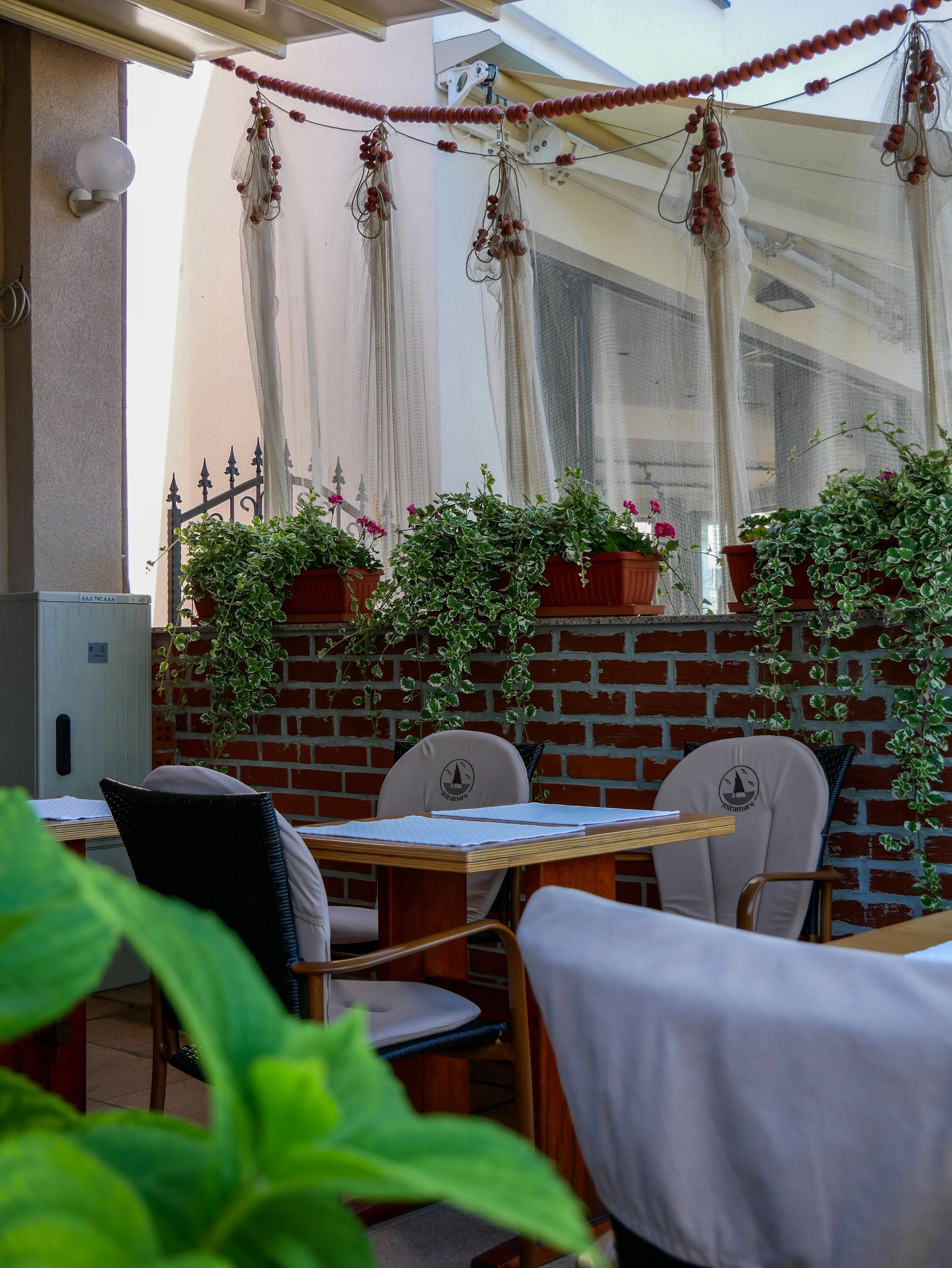 An outdoor seating area with brick walls, potted plants, and a table with chairs.