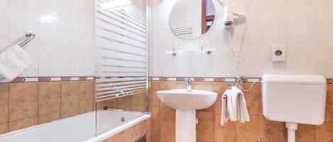 A modern bathroom with a bathtub, a pedestal sink, a toilet, and a shower with a glass door.